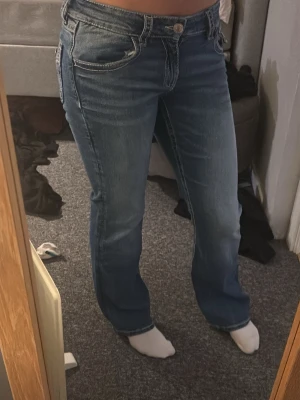 Blå bootcut jeans med broderade fickor - Säljer ett par blå bootcut jeans med snygga broderade bakfickor från Gina tricot. Passar xs. Inga defekter 