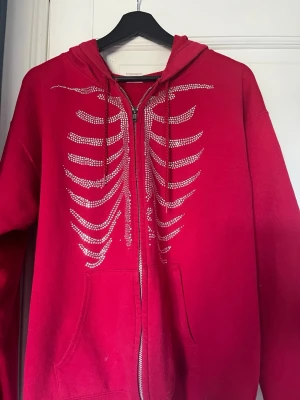 Röd hoodie 70kr - En hoodie med skelettmönstet, andvänd få gånger av mig, köpt den tidigare på plick. Storlek M tror jag, alla kläder tvättas innan.