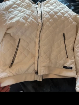 Vit quiltad bomberjacka Magiano - Säljer en snygg vit bomberjacka från Magiano med quiltat mönster och dragkedja framtill. Jackan har ribbade muddar och en praktisk sidoficka med dragkedja. Perfekt för dig som vill ha en stilren och bekväm jacka i lätt material. ( har nån blå otydlig fläck de sista bild, syns knappt) står storlek 42 men passar bra för s/m oxkså