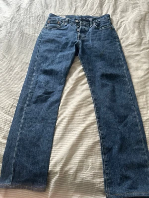 Blå raka jeans från Levi's - Klassiska blå jeans från Levi's med rak passform och knappgylf. Jeansen har fem fickor och är tillverkade i slitstark denim. Perfekta för en avslappnad och tidlös stil.