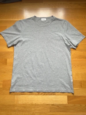 Grå t-shirt ifrån Wood Wood  - En stilren grå t-shirt. Mycket bra och fint skick. Kom gärna privat om du undrar något. 