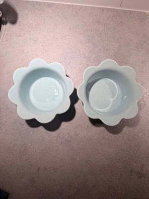 Blå blomformade skålar Piccadilly från Pernilla Wahlgren  - Två ljusblå skålar i keramik från Piccadilly, designade av Sagaform och Pernilla Wahlgren. Skålarna har en söt blomformad kant och är perfekta för snacks, godis eller små tillbehör. Unik design som piffar upp dukningen.