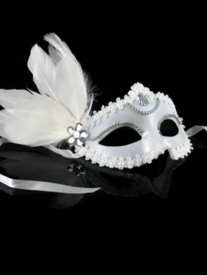 Vit maskeradmask med fjädrar - Elegant vit maskeradmask med dekorativa fjädrar och blommor på sidan. Masken har silverfärgade detaljer och kantband, samt satinband för att knyta runt huvudet. Perfekt för cosplay eller maskerad med stil.