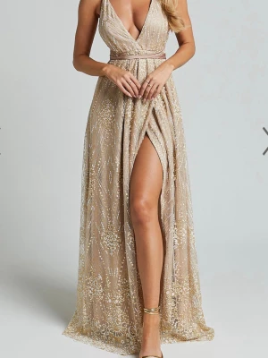 Champagnefärgad långklänning med slits - Säljer en HELT NY champagnefärgad långklänning med djup v-ringning, öppen rygg och tunna axelband. 🩷Klänningen har glittrigt mönster, markerad midja och hög slits framtill. Perfekt för dig som vill sticka ut på bal eller fest. ☀️Banden går att knyta på många sätt. Inköpspris- 1200kr.💌Storlek S, jag är 165cm. Skriv för andra frågor!!