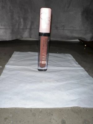 Matt flytande läppstift från Catrice - Säljer ett matt flytande läppstift från Catrice i färgen 'Vini Everyday', en snygg brunrosa nyans. Förpackningen är fyrkantig med genomskinlig kropp och roséguldfärgat lock. Håller upp till 12 timmar och har en smidig applikator för enkel applicering.