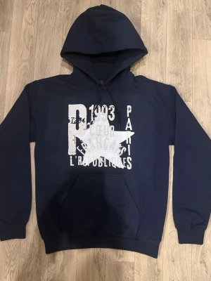 Navy Blue Paris Star Hoodie – Size S  - Storlek: S Färg: Navy Blue Skick: Helt ny, endast testad  Mått: Bröst: 49 cm Axelbredd: 51 cm Längd: 65 cm Ärmlängd: 60 cm Midja: 39 cm  Stilren och clean hoodie i mörkblå färg med “Paris Star” tryck ⭐ Perfekt basic som passar till allt – funkar både casual och streetwear.  Skön passform och bra kvalitet. Säljes då den inte används.