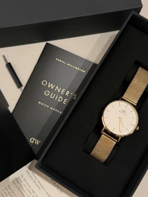 Guldig meshklocka från Daniel Wellington - Stilren klocka från Daniel Wellington med guldig mesh-länk och vit urtavla. Köpt för 1699