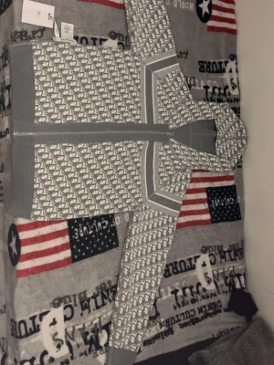Grå hoodie med elefantmönster - Säljer en grå hoodie från Dale of Norway med vitt elefantmönster över hela plagget. Hoodien har dragkedja framtill, ribbade muddar och en stor huva. Materialet är mjukt och stickat, perfekt för dig som gillar unik design och sköna plagg.