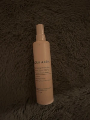Värmeskyddsspray från Björn Axén - Värmeskyddsspray från Björn Axén i en beige plastflaska med spraymunstycke. Perfekt för att skydda håret mot värmeverktyg upp till 220°C. Enkel att använda och smidig att ta med i väskan.