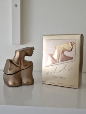 Eilish parfym av Billie Eilish 30ml - Unik parfymflaska i bronsfärgad metall och glas, formad som en byst. Eilish av Billie Eilish är en Eau de Parfum på 30 ml. Flaskan har en cool och modern design som sticker ut i parfymhyllan. 