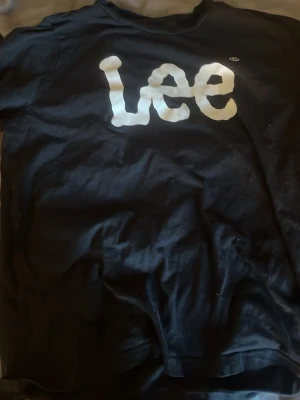 Svart t-shirt från Lee med tryck - Svart t-shirt från Lee med stort vitt logotryck på bröstet. Modellen är regular fit och tillverkad i ekologisk bomull. Perfekt för en avslappnad och stilren look.