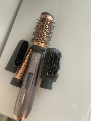 BaByliss varmluftsborste med tillbehör - Multifunktionell varmluftsborste från BaByliss i metallicgrå och kopparfärg. Inkluderar flera utbytbara borsthuvuden och munstycken för styling. Perfekt för att fixa håret snabbt och enkelt hemma. Har använt många gånger 