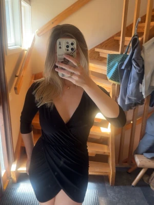 Svart omlottklänning med v-ringning - Svart kort omlottklänning med djup v-ringning och trekvartsärm. Mycket stretchig och sitter som en Medium 🌻