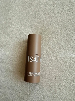 Isadora Contour Stick Bronzer - Krämig contour stick från Isadora i en snygg brun nyans. Perfekt för att skulptera och definiera ansiktet. Kommer i en smidig, rund hylsa av plast med vit text. Enkel att applicera och blenda för ett naturligt resultat. Endast testad på handen