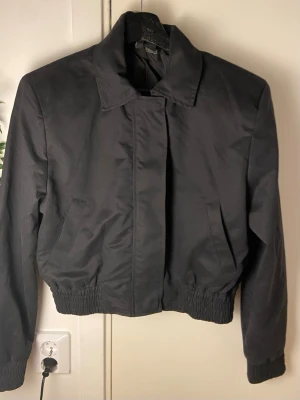 Svart bomberjacka med krage - En svart bomberjacka med krage med skönt material och fickor. Med scrunch vid händerna & längst nere på jackan. Helt ny och använd en gång. Silver detaljer!