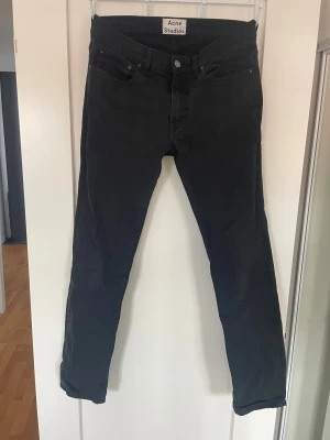 Svarta jeans från Acne Studios - Säljer ett par svarta jeans från Acne Studios med klassisk femficksmodell och slim ben. Jeansen är tillverkade i ett mjukt denimtyg som sitter snyggt. W31 L32. Finns en reparation under gylfen 