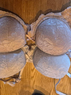 2 spetsbhar i pastellfärger med rosett - Två vadderade bhar i pastellrosa och ljuslila med vacker spets och små rosetter framtill. Båda har justerbara axelband och hakknäppning bak. Perfekta för dig som gillar romantisk och feminin stil.    Alla kläder rollas innan dom skickas hem då det finns katt i hemmet🐈 Jag stryker och tvättar INTE innan jag skickar det får du stå för själv så det blir som du vill ha det🤗