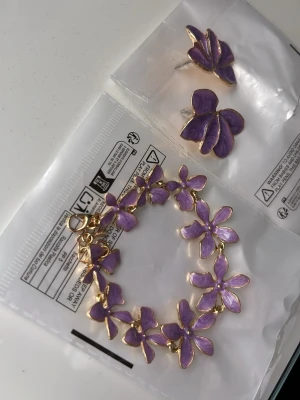 Armband & örhängen - Lila armband & blomformade örhängen. Oanvända.