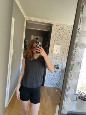 Mörkgrå ärmlös väst - En enkel och stilren mörkgrå ärmlös topp med rund hals. Toppen har en loose passform och är tillverkad i ett mjukt material som känns bekvämt mot huden. 