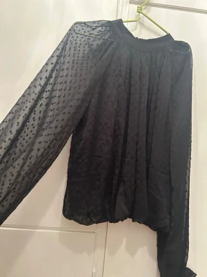 Svart transparent blus med prickar - Säljer en svart blus långärmade ärmar och diskreta prickar i tyget. Superfin till vardags men även festliga tillfällen i storlek xs, säljer den då den inte är min stil längre och knappt kommit till användning!🥰