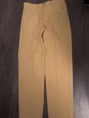 Beiga chinos från Marlboro Classics - Snygga beiga chinos från Marlboro Classics med klassisk rak passform. Tillverkade i ett mjukt och slitstarkt bomullstyg. Perfekta för en clean och avslappnad stil. Fina detaljer och diskret logga på insidan. Storlek 46 ( verkar vara typ w30, L32)