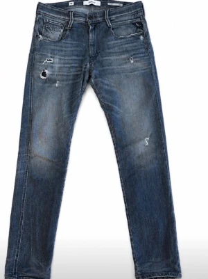 Blå slitna jeans med hål - Snygga blå jeans med slitningar och hål på låret och knät. Jeansen har klassisk femficksmodell, raka ben och en tvättad look. Perfekta för en avslappnad och trendig stil.