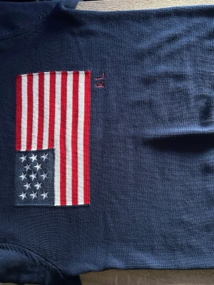Ralph Lauren stickad tröja – Storlek M - Säljer en stilren och välvårdad Ralph Lauren-tröja i storlek M. Tröjan är endast använd vid två tillfällen och är därför i mycket fint skick, nästintill som ny.  ✔ Endast använd 2 gånger ✔ Inga hål, fläckar eller andra skador ✔ Mjuk och bekväm passform ✔ Klassisk Ralph Lauren-design med amerikansk flagga på bröstet ✔ Färg: Marinblå  Perfekt för både vardag och mer uppklädda tillfällen.