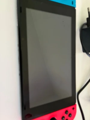 Nintendo Switch med laddare - Nintendo Switch spelkonsol med neonblå och neonröd Joy-Con. Konsolen har en rektangulär form med stor skärm och knappar på sidorna. Materialet är plast och glas. Laddare medföljer. Perfekt för gaming på språng eller hemma.