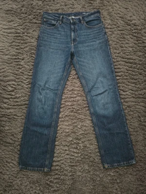 Blå loose fit jeans klassiska W30 / L32 - Säljer ett par blå jeans med raka ben och klassisk femficksdesign. Jeansen har normal midja och är tillverkade i denim med tydliga sömmar. Perfekta för dig som gillar en enkel och tidlös stil. 