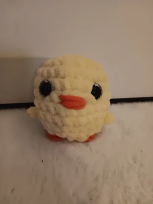 Gullig virkad kyckling - Söt handgjord kyckling i mjukt, gult garn med stora svarta ögon och orange näbb och fötter. Perfekt som dekoration eller present. Rund form och små vingar på sidorna.