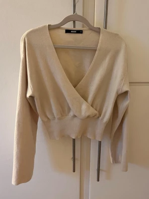 Beige topp - Beige omlottopp med djup V-ringning och ribbad midja