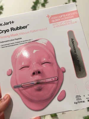 Dr.Jart+ Cryo Rubber Firming Mask - Dr.Jart+ Cryo Rubber Firming Mask är en ansiktsmask med adenosine plus peptid som ger synlig uppstramning och glowig återfuktning. Förpackningen är vit med rosa detaljer och innehåller en ampull och en gummiliknande mask.