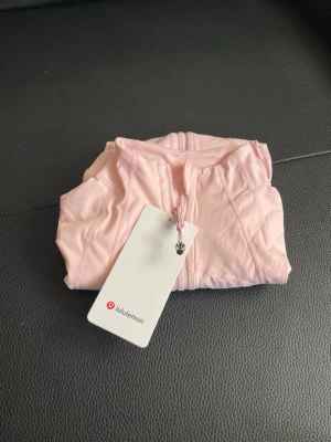  Lululemon define jacket  - Supersnygg ljusrosa ziptröja från Lululemon med figurnära passform och långa ärmar. Tröjan har dragkedja framtill, hög krage och praktiska fickor med dragkedja. Tillverkad i ett stretchigt och mjukt material som passar perfekt till träning eller chill. Priset kan diskuteras vid seriös köpare 