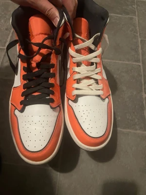 Air Jordan 1 Orange/White/Black Highs - Säljer ett par Air Jordan 1 helt nya, testat 1 gång. Bytt till off-white snöre på ena skon. 