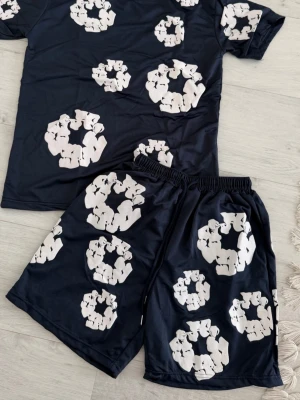 Svart pyjamasset med björnmönster - Coolt pyjamasset med svart t-shirt och shorts, dekorerat med stora vita björnmönster i cirklar. Perfekt för chillkvällar hemma. Mjukt och lätt material som känns skönt mot huden.