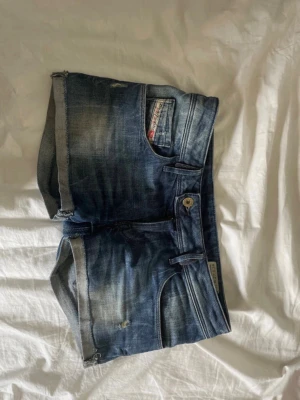 Blå jeansshorts från Diesel - Säljer ett par blå jeansshorts från Diesel med klassisk femficksdesign och slitna detaljer. Storlek S men sitter nästan som XS. 
