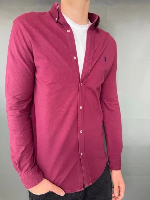 Ralph Lauren skjorta - Ralph Lauren skjorta Märke: Polo Ralph Lauren Storlek: S Passform:  Färg: Vinröd Skick: Bra Beskrivning: Feather weightmesh, lite missfärgad vid ärmarna. Modellen på bilden: 183 cm/ 75 kg