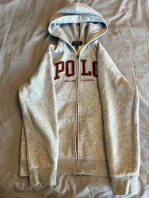 Polo ralph lauren zip-hoodie - Säljer en polo ralph lauren hoodie som har använts väl och skonsamt, tröjan har inga större defekter eller slitage. Tröjan är lite liten i storleken.  Anledningen till att varan säljs är att den ej passar längre. Vid frågor eller funderingar är det bara att skriva!