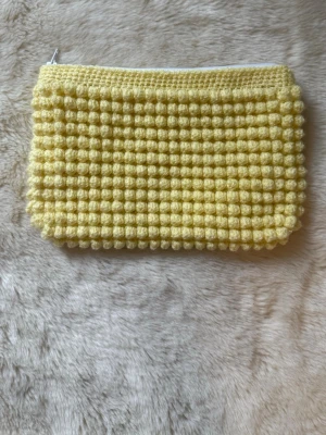 Virkad necessär  - Necessär med virkat bubbelmönster och dragkedja upptill. Perfekt att bära i handen för en trendig och lekfull look.