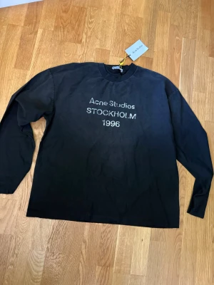 Svart långärmad tröja Acne Studios - Cool svart långärmad tröja från Acne Studios med texten 'STOCKHOLM 1996' broderad på bröstet. Tröjan har en klassisk rund halsringning och är tillverkad i mjukt material som känns skönt mot huden. Perfekt för dig som gillar stilrena plagg med en touch av streetwear. Priset kan diskuteras 