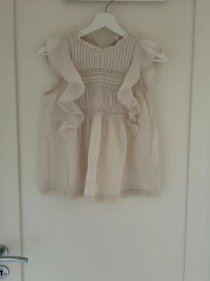 Beige blus med volangdetaljer - Söt beige blus med volanger längs axlarna och fina spetsdetaljer. Strl. XS💗