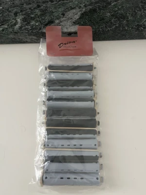 Heatless curls redskap  - Ett paket med hårspolar i olika nyanser av grått från Driva Collection. Perfekta för att skapa lockar eller volym i håret utan värme. Spolarna är av plast och har klassisk avlång form med små hål för bättre grepp och luftgenomsläpp.
