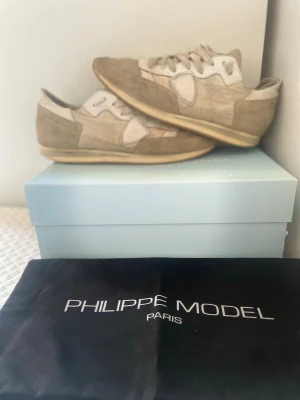 Philippe Model beige sneakers - Snygga runners från Philippe Model i beige och vitt mocka och läder. Klassisk låg modell med vita snören och diskret logga på sidan. Skorna har en smal defect på sidan av den vänstra skon och bå vardera hälar, samt så har nåda tygen där hälen sitter gått up.✨skriv gärna om du har frågor eller om du vill diskutera prise/fler bilder✨