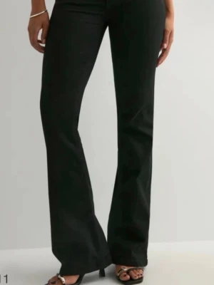 Svarta bootcut jeans - Snygga svarta bootcut jeans med hög midja och utsvängda ben. Jeansen har klassisk femficksdesign och stängs med dragkedja och knapp. Perfekta för dig som vill ha en trendig siluett och matcha med sneakers eller klackar.