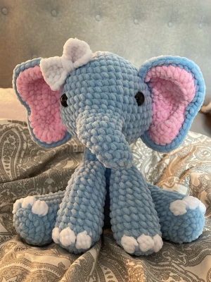 Blå virkad elefant med rosett - Supergullig virkad elefant i mjukt blått garn med stora rosa öron, vita tassar och en söt vit rosett på huvudet. Perfekt som dekoration eller mysig present. Första gången jag testar detta mönster så det kan finnas lite skavanker. Därav billigt pris. 