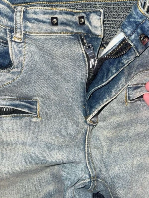 Ljusblå bikerjeans från Balmain - Säljer ett par ljusblå bikerjeans från Balmain med dragkedjor vid fickorna, detaljerade sömmar vid knäna och smal passform. Klassisk Balmain-lapp bak i midjan och coola detaljer som ger en edgy look.