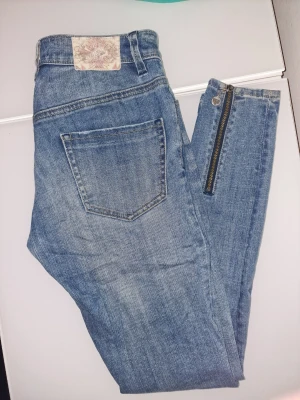 Blå jeans med dragkedja Odd Molly - Snygga blå jeans från Odd Molly med en cool dragkedjedetalj vid benet. Perfekta för dig som vill ha en unik twist på dina vardagsjeans.