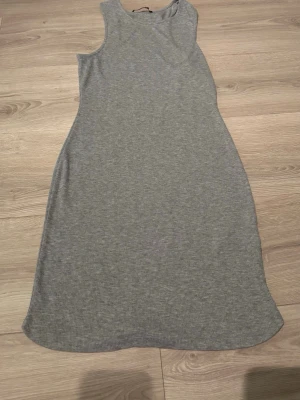 Grå snygg  ribbad  klänning - En enkel och stilren grå klänning i ribbad bomull. Klänningen är ärmlös med rund halsringning och har en rak, något lös passform som slutar ovanför knäna. Perfekt för en avslappnad look.
