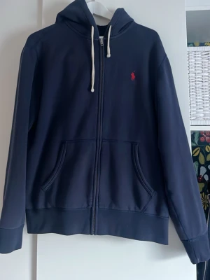 Mörkblå hoodie från Ralph Lauren - Snygg mörkblå hoodie med dragkedja från Ralph Lauren. Klassisk modell som aldrig går fel! 