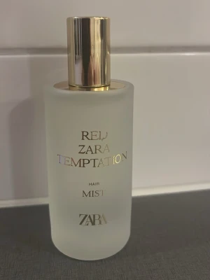 ZARA Red Temptation Face Mist - Lyxig hair mist från ZARA i serien Red Temptation. Flaskan är frostad och vit med guldfärgad text och lock. Ger en fräsch känsla och kommer i en stilren, rund flaska som känns exklusiv och modern. Perfekt för att fräscha upp huden under dagen.